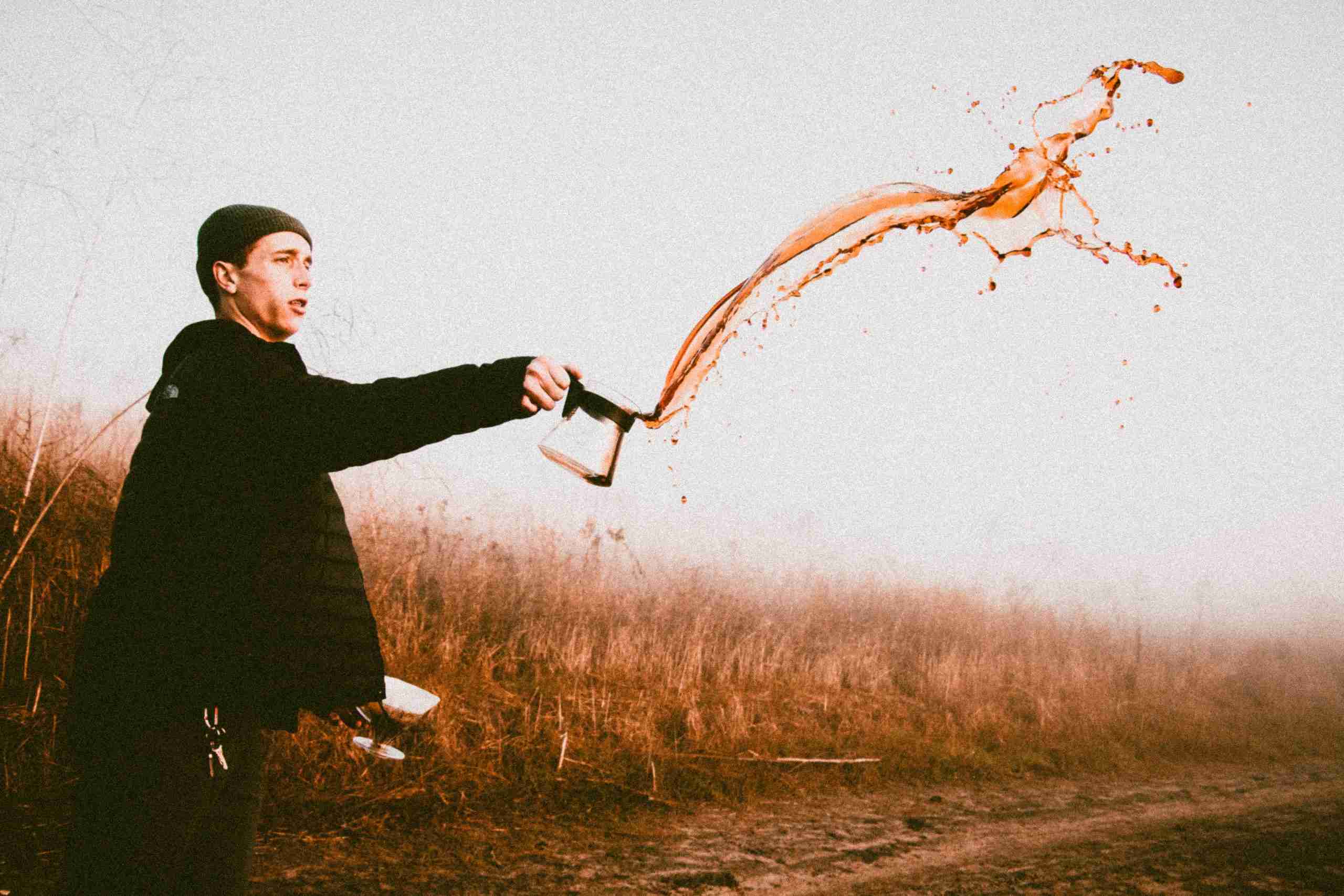 man throwing out carafe full of coffee into the air