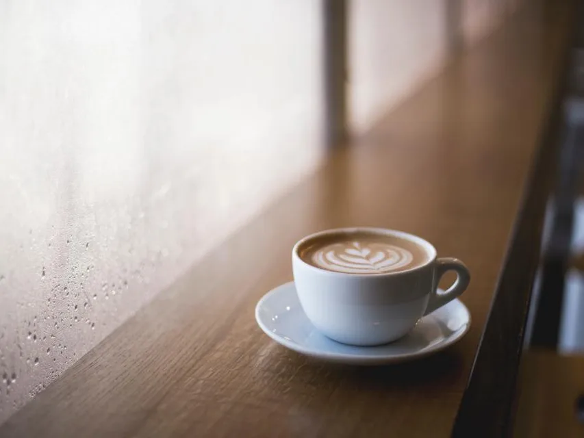 Does Humidity Affect Coffee? Why It Tastes Different on Humid Days 1 Latte on a wooden counter beside a rain-streaked window