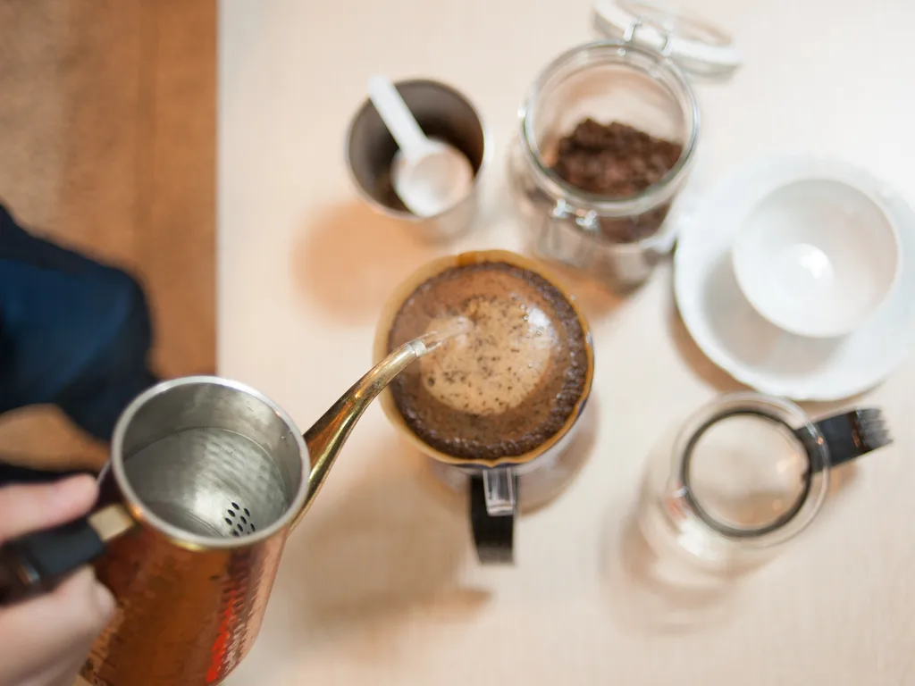 Overhead view of hot water being poured over coffee grounds in a pour-over dripper